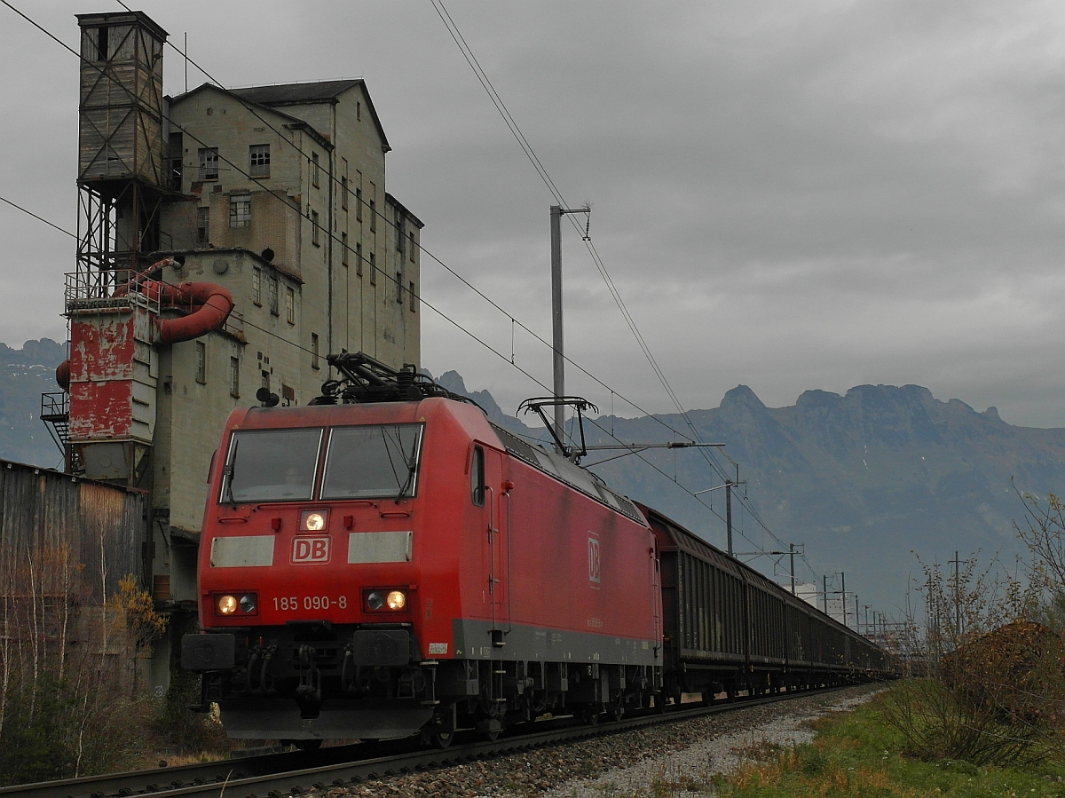 185 090-8 zieht einen Schiebewandwagenganzzug kurz nach der Abfahrt im Bahnhof von Buchs am 15.11.2014 am alten Fabrikgebäude der ehemaligen Basaltstein AG vorbei.