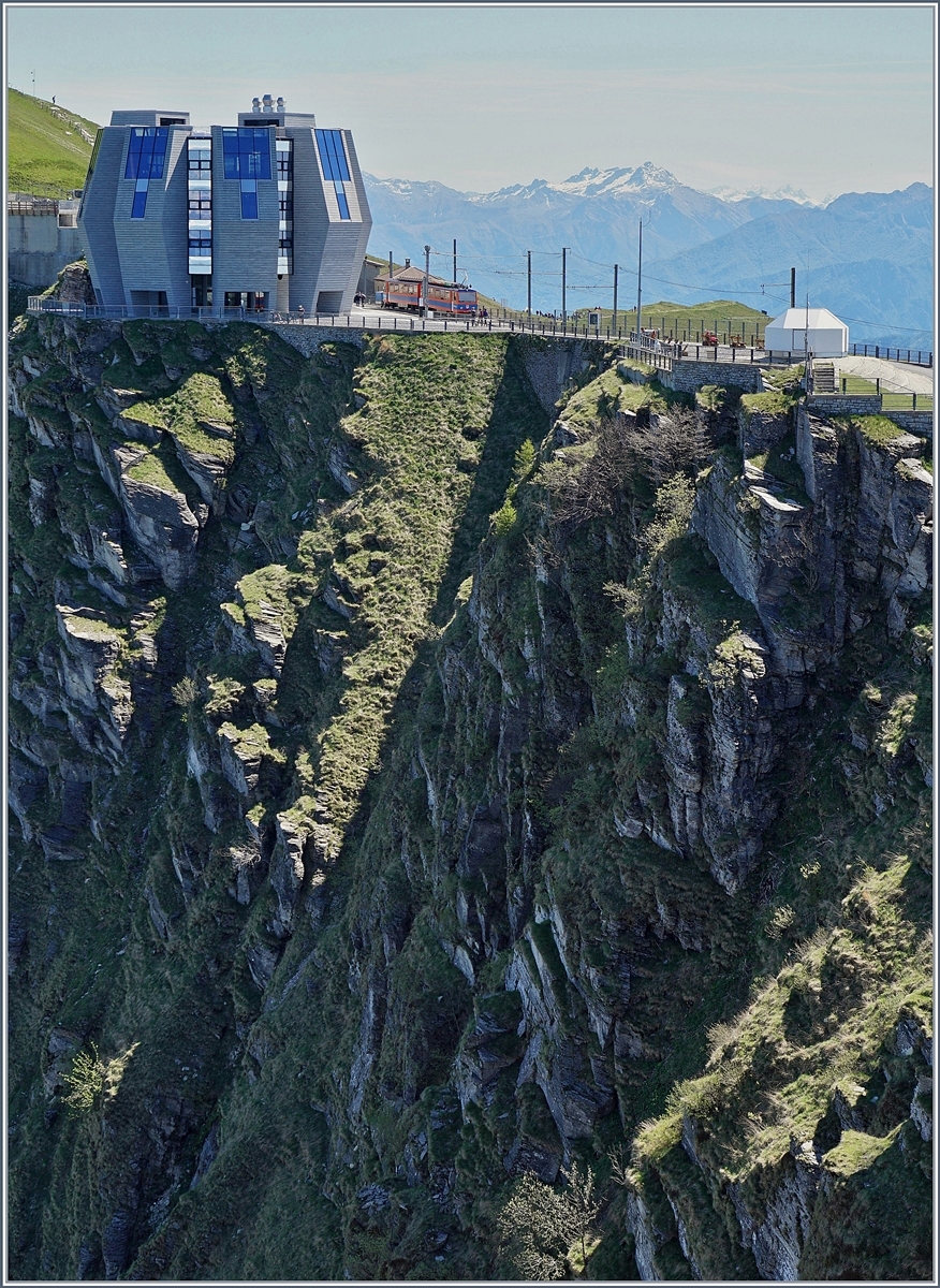 Aus dieser Perspektive zeigt sich die harmonische Schönheit der aufblühenden  Knospe  von Mario Bottas  Fiore di pietra  in Generoso Vetta auf 1705 müM. 
Im Bahnhof wartet ein Beh 4/8 auf die Talfahrt. 
21.Mai 2017