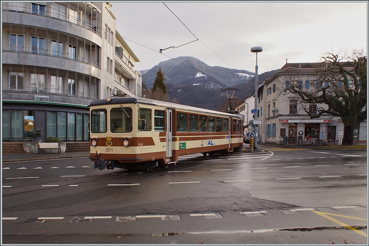 Der TPC A-L Regionalzug 329 von Leysin nach Aigle bestehet aus dem Bt 351 und dem BDeh 4/4 302. Der Zug hat den Halt Aigle-Place-du-Marché verlassen und überquert nun eine Kreuzung um dann durch die Altstadt zum Bahnhof von Aigle zu kommen. 

5. Dezember 2021