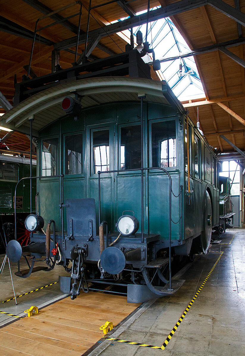 Die Drehstrom- Elektrolokomotive ex BTB De 2/2 Nr.1, ex BTB F 2/2 Nr. 1 (1902 – 1922), ex BTB E2E Nr. 1 (bis 1902), am 11.09.2022 in der Lokwelt Freilassing. Die Lok ist Eigentum des Deutschen Museums - Verkehrszentrum in München und eine Leihgabe die Lokwelt Freilassing

Dem Güterverkehr der Burgdorf-Thun-Bahn (BTB) dienten zwei Lokomotiven vom Typ F 2/2. Bis 1902 wurden sie als E2E bezeichnet, ab 1922 als De 2/2. Diese beiden ersten in der Schweiz, im Jahr 1899, gebauten elektrischen Lokomotiven (De 2/2 Nr.1 und  2) waren eine gemeinsame Konstruktion der Schweizerischen Lokomotiv- und Maschinenfabrik (SLM) in Winterthur für den mechanischen Teil und der Brown, Boveri & Cie. (BBC) für die elektrische Ausrüstung. 

Der noch nicht ausgereifte Einphasen-Wechselstrom-Betrieb konnte zur damaligen Zeit noch nicht eingesetzt werden. Deshalb beschaffte die Schweizer Burgdorf-Thun-Bahn (BTB) zunächst für den reinen Güterzugbetrieb zwei dieser mit Drehstrom (Dreiphasenwechselstrom) angetriebenen Lokomotiven. Das Drehstrom-System konnte nur in einem bestimmten Geschwindigkeitsbereich effektiv arbeiten, so dass ein mechanisches Schaltgetriebe für zwei maximale Geschwindigkeiten notwendig war, nämlich für 18 und 36 km/h.

Ab 1933 wurde der Drehstrombetrieb auf dieser Strecke eingestellt und die beiden Lokomotiven ausgemustert. Die beiden Lokomotiven sind als weltweit erste Drehstromlokomotiven für den Vollbahnbetrieb erhalten geblieben. Die Nr. 1 befindet in der Lokwelt Freilassing, die Nr. 2 befindet sich im Verkehrshaus der Schweiz in Luzern.

Die beiden Motoren wiesen eine Leistung von je 150 PS (110 kW) auf. Das nur im Stillstand umschaltbare Getriebe ermöglichte zwei Geschwindigkeiten, Die eine bis 18 km/h ließ auf der größten Steigung von 25 ‰ eine Anhängelast von 100 Tonnen zu, die andere bis 36 km/h noch die Hälfte. Wobei die zulässige Höchstgeschwindigkeit betrug 50 km/h, so wurde in den späteren Betriebsjahren in Gefällen stromlos gefahren, um diese zu erreichen. Dank der höheren Geschwindigkeit hätten die Lokomotiven nötigenfalls auch im Personenverkehr Verwendung finden können.

Die beiden 19-poligen Triebmotoren sind beidseits auf einer auf einem Hilfsgestell gelagerten gemeinsamen Welle montiert. Über ein Vorgelege wurde das Drehmoment mittels Kuppelstangen auf die beiden Achsen übertragen. Zum Anfahren war ein für beide Motoren gemeinsamer Widerstand vorhanden, der mit dem in jedem Führerstand vorhandenen Kontroller allmählich ausgeschaltet wurde. Beleuchtung, Heizung und Hilfsbetriebe wurden mit einer Spannung von 100 Volt betrieben. Die Lokomotiven weisen an beiden Enden offene Plattformen auf. Die vier Schleifbügel auf dem Dach legten sich selbsttätig beim Wechsel der Fahrtrichtung nach hinten um. Zum Abbügeln mussten die an den Bügeln angebrachten kurzen Zugseile vom Boden aus mit hölzernen Stangen heruntergezogen und in Arretierhaken eingehängt werden.

TECHNISCHE DATEN:
Baujahr: 1899, Ausmusterung1930
Spurweite: 1.435 mm (Normalspur)
Achsfolge: B
Länge über Puffer: 7.800  mm
Achsabstand: 3.140 mm
Treibraddurchmesser:  1.230 mm
Dienstgewicht: 29.600 kg
Höchstgeschwindigkeit: 18 km/h / 36 km/h (stromlos bergab 50 km/h)
Stundenleistung: 300 PS (220 kW)
Stundenzugkraft: 4.400 daN
Stromsystem: 750 V, 40 Hz ∆
Anzahl der Fahrmotoren: 2
Übersetzungsstufen: 2 (für 18 / 36 km/h)

Die Burgdorf-Thun-Bahn (BTB) war eine Eisenbahngesellschaft in der Schweiz. Ihre Strecke von Burgdorf über Konolfingen nach Thun wurde als erste elektrische Vollbahn der Schweiz im Jahr 1899 dem Betrieb übergeben. Heute ist sie Bestandteil der BLS AG