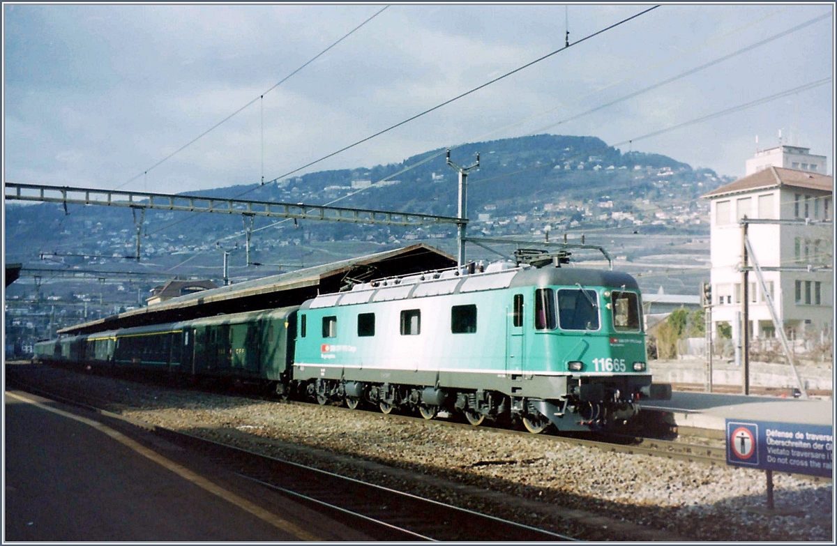 Die SBB Re 6/6 11655 in der gefälligen, aber dann verworfen Cargo Lackierung mit einem Schnellzug nach Brig beim Halt in Vevey. 

Das Bild entstand im Frühling des Jahres 2000 in Vevey. 

