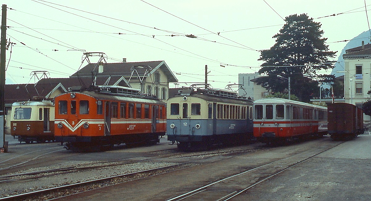 Leider nur bei nicht optimalen Lichverh�ltnissen war diese Aufnahme des Bahnhofsvorplatzes von Aigle im Mai 1980 m�glich: Von links nach rechts BDeh 2/4 202 der AL, ABDe 4/4 3 und der weitgehend im Originalzustand erhaltene ABFe 4/4 12 der ASD und ganz rechts zwei Beiwagen der AOMC. An dieser Stelle eine Anmerkung: Die Triebwagen 2, 11 und 12 der ASD waren bei meinen beiden Besuchen im Gegensatz zu den anderen Fahrzeugen als ABFe 4/4 beschriftet.