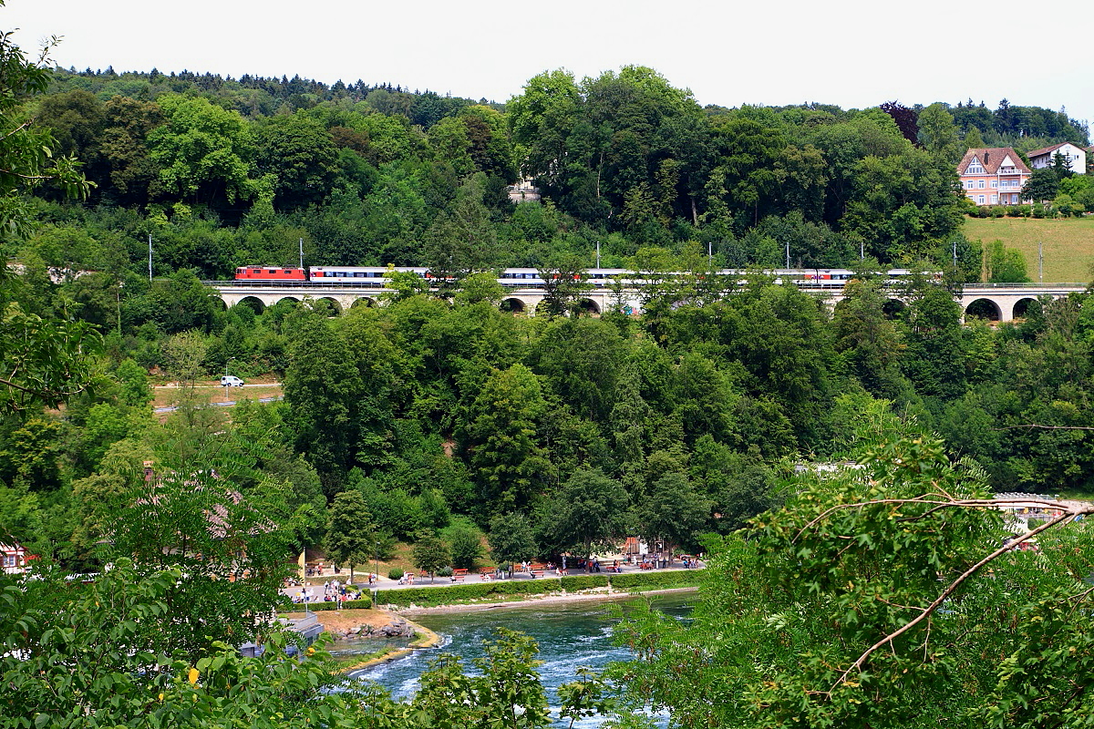 Mit einem EC nach Z�rich ist eine Re 4/4 II am 26.07.2015 oberhalb des Rheinfalls unterwegs, die Aufnahme entstand vom Bahnsteig des Haltepunktes Schloss Laufen aus