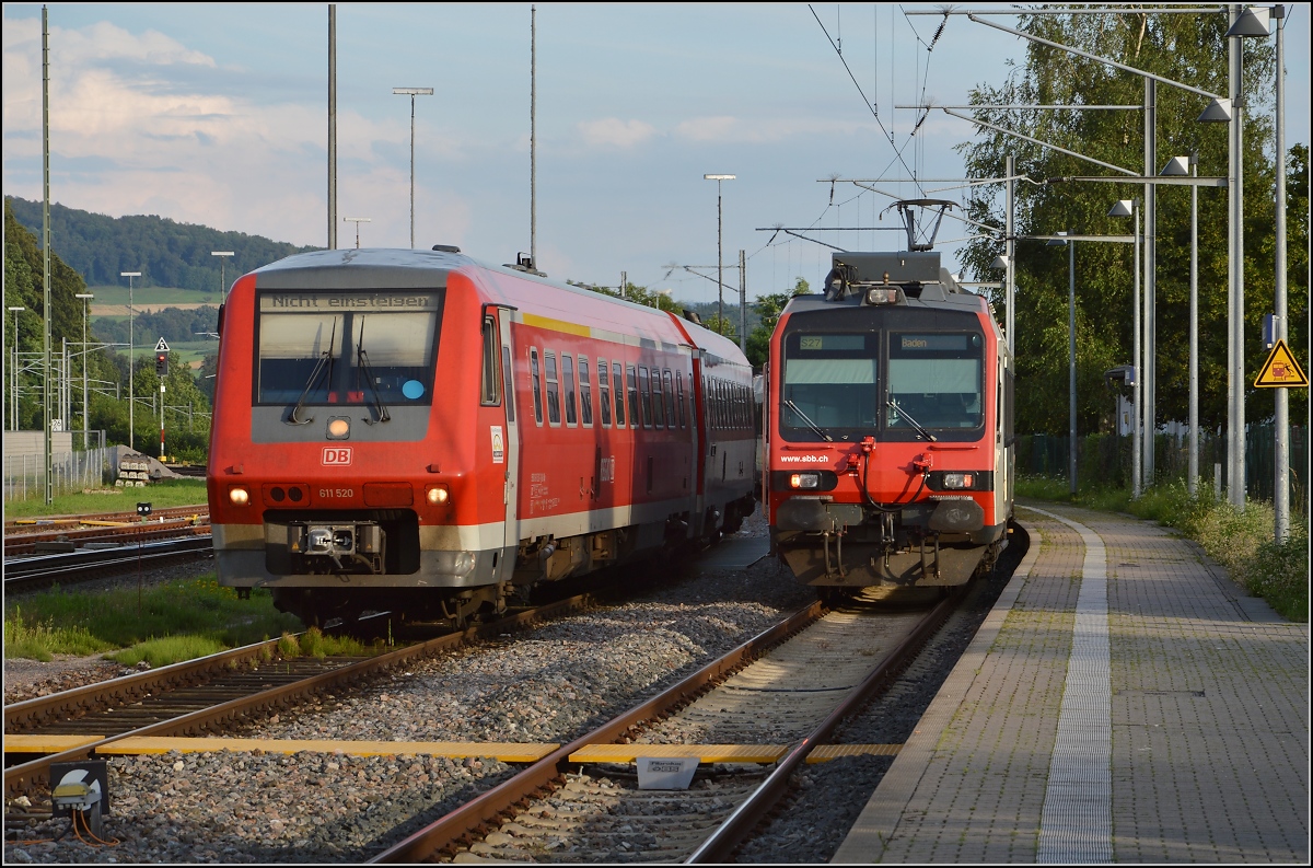 Obwohl die historische Brücke Waldshut-Koblenz schon deutlich altersmüde ist, Baujahr 1859, fahren immer noch die schweren NPZ-Domino darüber, dieser sogar in Doppeltraktion. Seit 1999 ist Gleis 1 gekappt und von der Schweizer Seite her elektrisch erreichbar, nunmehr als Gleis 5. Nebenan steht 611 020 beim Tanken. Waldshut, Juli 2016.