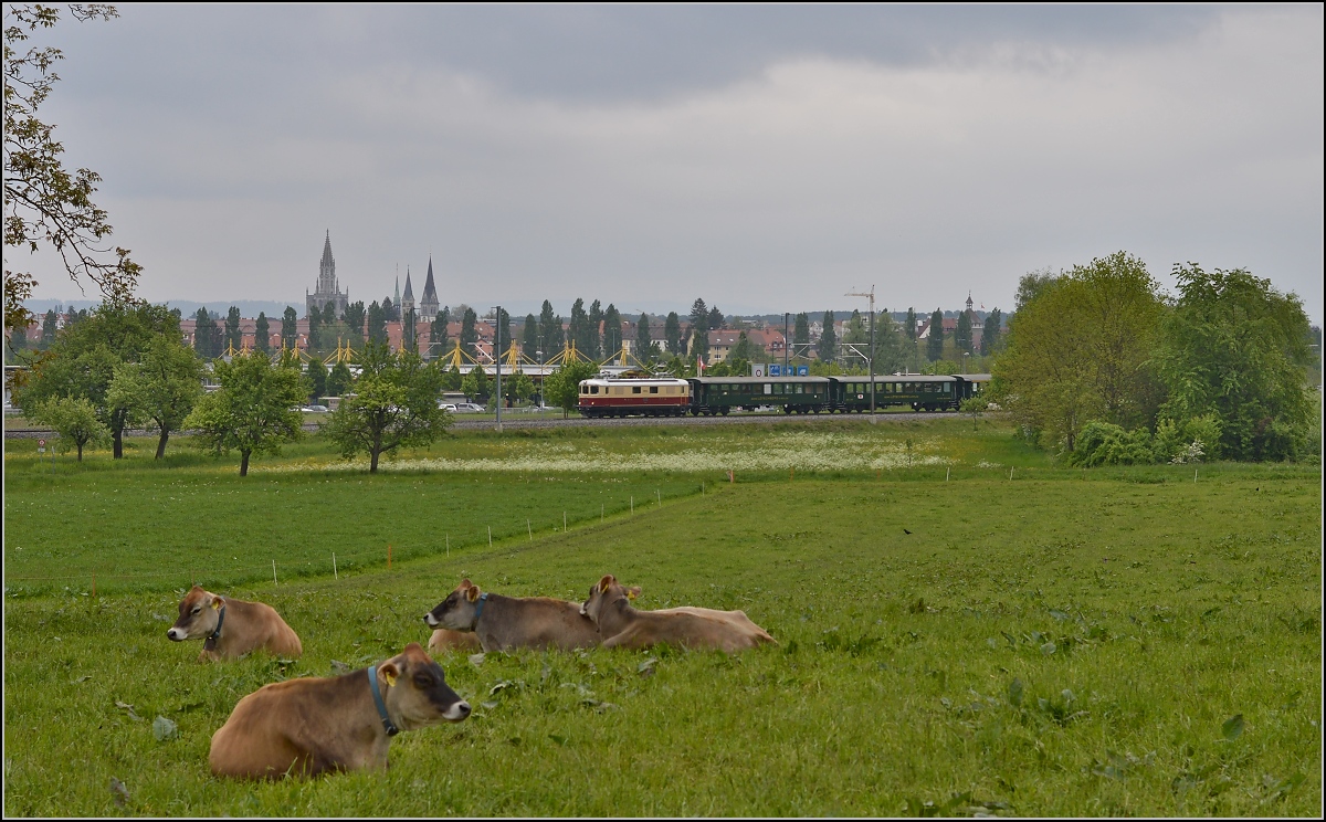 TEE am See. Die Re 4/4 I 10034 im Rot/Creme-Gewand und historischen SBB-Wagen im Tägermoos. Im Hintergrund die Skyline von Konstanz. Damit man aber den Standort Schweiz erkennt, hatte ich vier Models gebeten ein wenig still zu halten. Mai 2014.