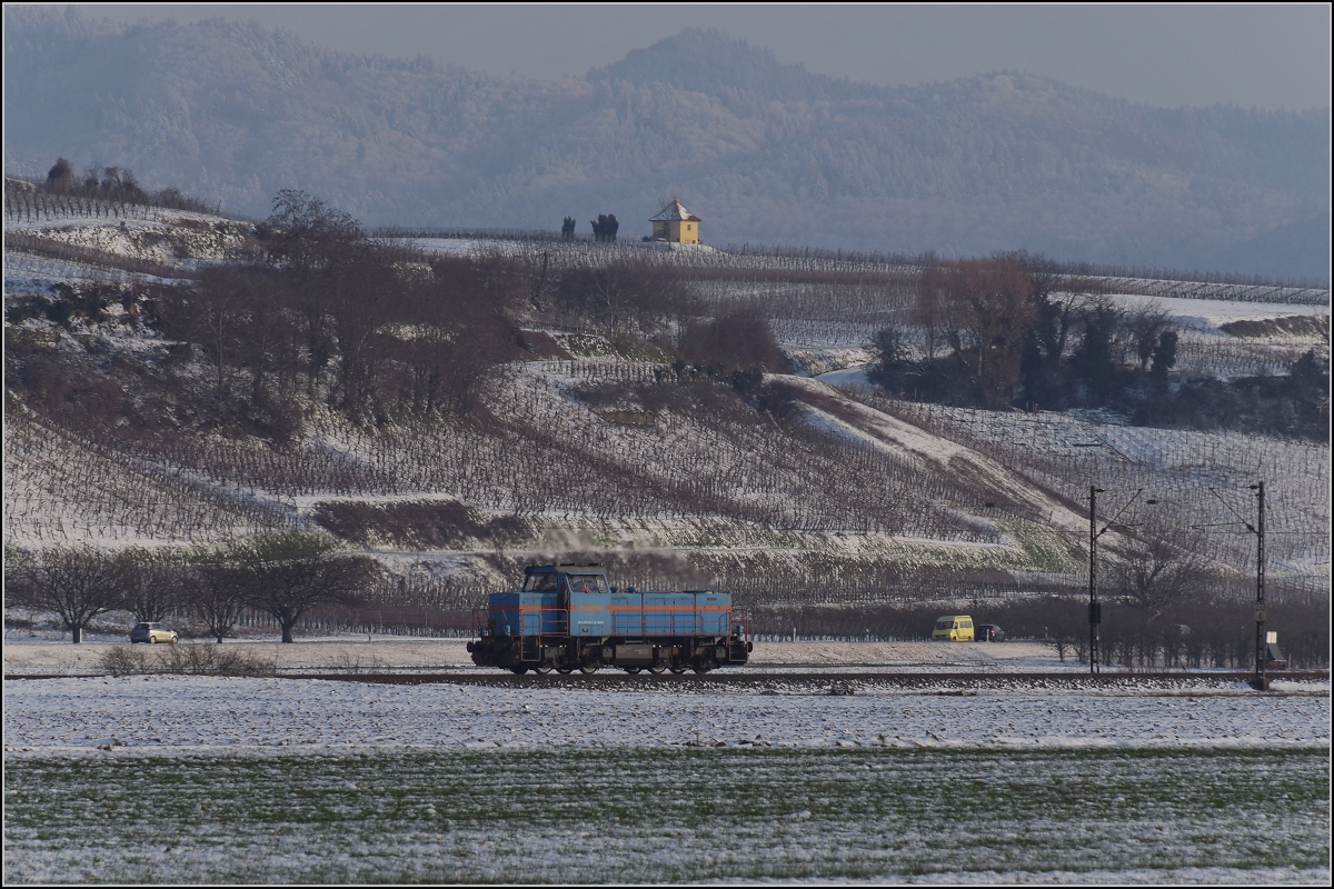 Zwischen Belchensystem und Blauendreieck. 

Eine kleine Lok auf der Magistrale Richtung Basel wird kurz vorher Richtung Neuenburg abbiegen. 0 580 003 der SWEG lässt den Blick auf die Landschaft des Markgräfler Landes völlig frei. Im Hintergrund das Rebhäusle und die Hügel rund um das Schloss Bürgeln. Buggingen, Februar 2021.