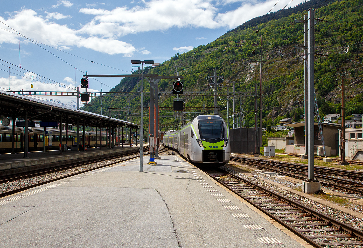 Der BLS MIKA 110 (in Regioexpress-Ausführung) - RABe 528 110 (94 85 7528 110-0 CH-BLS) erreicht am 25 Mai 2023, als RE von Bern via Spiez und Kandersteg nun den Bahnhof Brig (auf Gleis 9). Eigentlich sollten die BLS“MIKA” von Bern über die Lötschberg-Bergstrecke und Brig weiter bis nach Domodossola fahren, aber diese haben noch keine Zulassung für Italien, die sie hinter dem SBB) Simplontunnel bis Domodossola brauchen. Und so wird der Zuglauf in Brig gebrochen und die Reisende, die bis Domodossola wollen, müssen in einen am Gleis 8 bereitgestellten “NINA” umsteigen. 