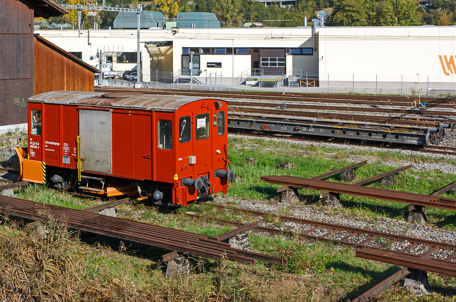 Der BLS Schneepflugwagen 99 85 9592 802-4 CH-BLS, Gattung X-v, ist am 02.10.2011 in Interlaken Ost, vor dem Depot der Ballenberg Dampfbahn (seit 01.01.2022 BDB - Brünig Dampfbahn BDB) abgestellt. Dahinter der normalspurige Rollwagen (Rollschemel) für den Transport von schmalspurigen Fahrzeugen, RIV - EUR  84 85 9918 603-1. Aufnahme aus einen fahrendem Zug.

TECHNISCHE DATEN vom Schneepflugwagen (gemäß Anschriften):
Spurweite: 1.435 mm (Normalspur)
Anzahl der Achsen: 2
Länge über Puffer: 8.540 mm
Eigengewicht: 20.500 kg
Max. Ladegewicht: 9.000 kg (ab Streckenklasse A)
Ladefläche: 17,7 m²

TECHNISCHE DATEN vom Rollwagen (gemäß Anschriften):
Spurweite: 1.435 mm (Normalspur)
Anzahl der Achsen: 4
Länge über Puffer: 18.300 mm
Achsabstand im Drehgestell: 3.000 mm
Laufraddurchmesser: 800 mm (neu)
Ladelänge: 17.600 mm
Eigengewicht: 26.290 kg
Max. Ladegewicht: 62,5 t (ab Streckenklasse C)
Max. Tragfähigkeit: 65,0 t
