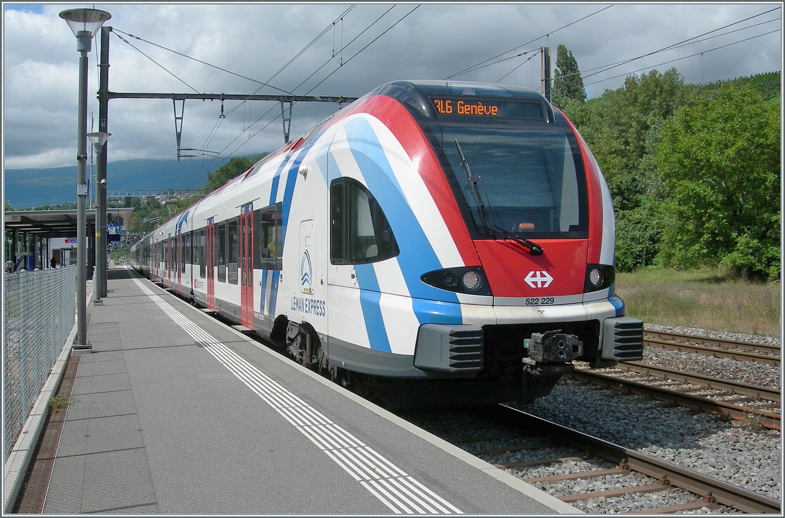 Der SBB -CFF LEX RABe 522 229 wartet als RL6 in La Plaine auf die Abfahrt nach Genève.
Dazu etwas Hintergrundinformation im wahrsten Sinne des Wortes: die  richtige  RL6 von Bellgarde nach Genève ist wage im Hintergrund zu sehen, es handelst sich im den SBB CFF LEX RABe 522 226 der als TERL6 96749 von Bellegarde um 13:01 in La Plaine angekommen ist und nun ins Taktgefüge des RL5 eingeflechtet wird, indem er mit dem hier wenden RL5 von Genève vereinigt wird und in La Plaine über zwanzig Minuten Aufenthalt hat. Diesen Aufenthalt war für mich erfreuliche und ich nutzte ihn für eine paar Bilder. 
Da der Zug nun zweiteilig nach Genève fährt, hat er auf dem kurzen  La Plaine  Gleis 6 keinen Platz und erreicht Genève auf Gleis 7, somit müssen hunderte von Schülern, die von der Mittagspause zurück zur Schule fahren durch die Zoll - und Passkontrolle...

26. August 2024