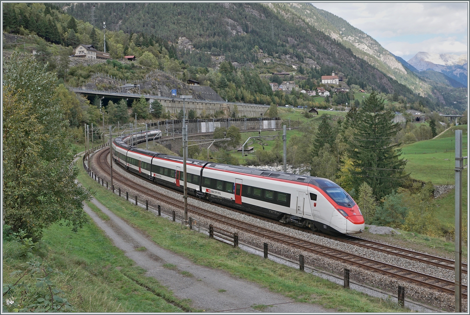Der SBB  Giruno  RABe 501 016  Glarus  ist als IC 2 von Zürich nach Lugano bei Wassen auf der untersten Ebene bei der Wattinger Kurve unterwegs. Im Hintergrund das Kirchlein von Wassen. Dreimal können die Reisenden eine Blick auf die Kirche von Wassen werfen, im Umkehrschluss aber auch der Betrachter dreimal den Zug betrachten d.h. auf jeder Eben, auch wenn der Standort bei der Wattingerkurve dafür nicht unbedingt prädestiniert ist.

19. Okt. 2023

