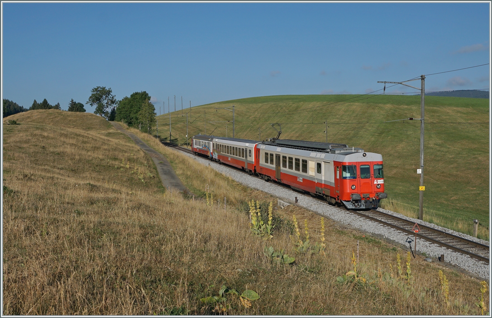 Der sogenannte  Schülerzug , bestehend aus dem ABt 375 (ABt 50 85 80 33 325-7), dem B 536 (B 50 85 2035 536-5 CH-TVYS) und dem TRAVYS RBDe 567 174 (94 85 7567 174-8)  Fleurier , ist als Regionalzug 6009 von Vallorbe nach Le Brassus kurz nach Les Charbonnières unterwegs. 

Es ist einer der letzten Planmässigen Einsätze des Zuges, mit dem neuen Fahrplankonzept der PBr wurde die Komposition überflussig.
Leider war der ABt und der B bereits verschmiert, das  Gesamtwerk  wurde aber durch die Bildbearbeitung seiner Aussagekraft beraubt. 

21. Juli 2022 