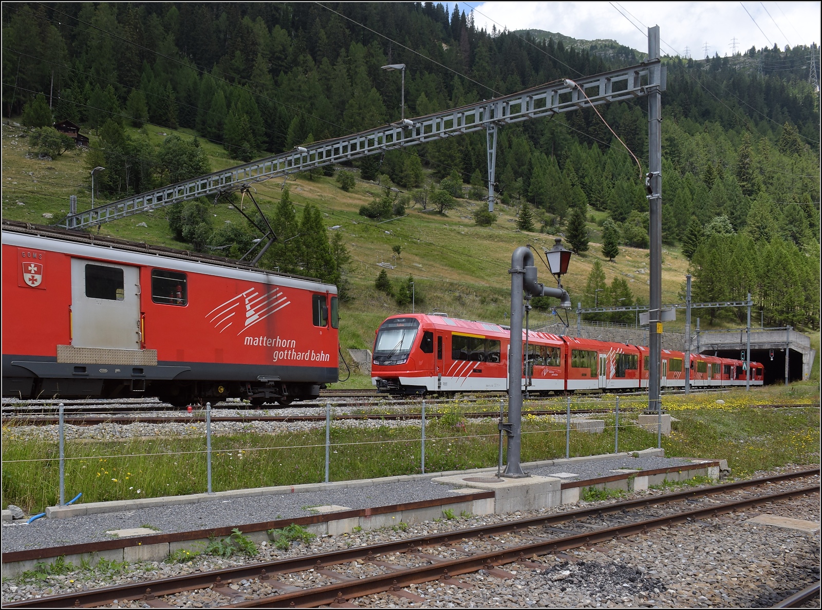 Die Ablösung macht sich parat: ABeh 8/12 Orion.

ABeh 8/12 301 und ABeh 8/12 302 begegnen auf ihrer Testfahrt dem Deh 4/4 I 54 'Goms' in Oberwald (im Goms). Juli 2023.
