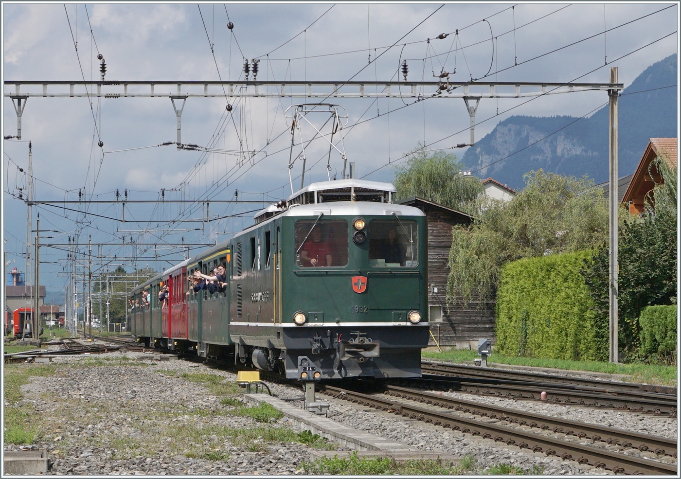 Endlich wieder einmal ein  echter  Brünig-Bahn-Zug in Meiringen! Die SBB HGe 4/4 I N° 1992  Giswil  erreicht mit ihrem Extrazug zum Jubiläum  20 Jahre Zentralbahn  den Bahnhof von Meiringen.
Die HGe 4/4 I 1992 Lok mit dem typischen SBB-Gesicht, ähnlich einer Ae 6/6 oder Re 4/4 II, wurde zusammen mit der HGe 4/4 1991  Meiringen  im Jahre 1954 beschafft, um auf der Bergstrecke der Brünigbahn die Deh 4/4 zu entlasten. Die Loks  sind so stark, dass sie einerseits den Namen  Muni  bekam, andererseits das Getriebe der Loks den vielen PS nicht ganz gewachsen war.  Muni  bedeutet soviel wie bulliger Stier.

23. August 2025