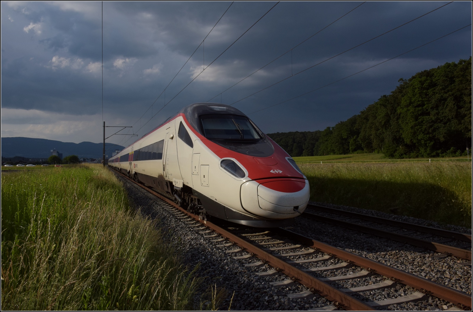 Fernverkehrstag auf der Altstrecke.

Via Burgdorf gibt es zumeist nur noch Güterverkehr, Nahverkehr und überregionale Züge nach Bern. Nicht an diesem Tag, RABe 503 016 ist diesmal gemächlicher Richtung Olten unterwegs. Während der Vorbeifahrt taucht er innerhalb von ein paar Metern in gewittrige Stimmung ein. Bettenhausen, Juni 2023.