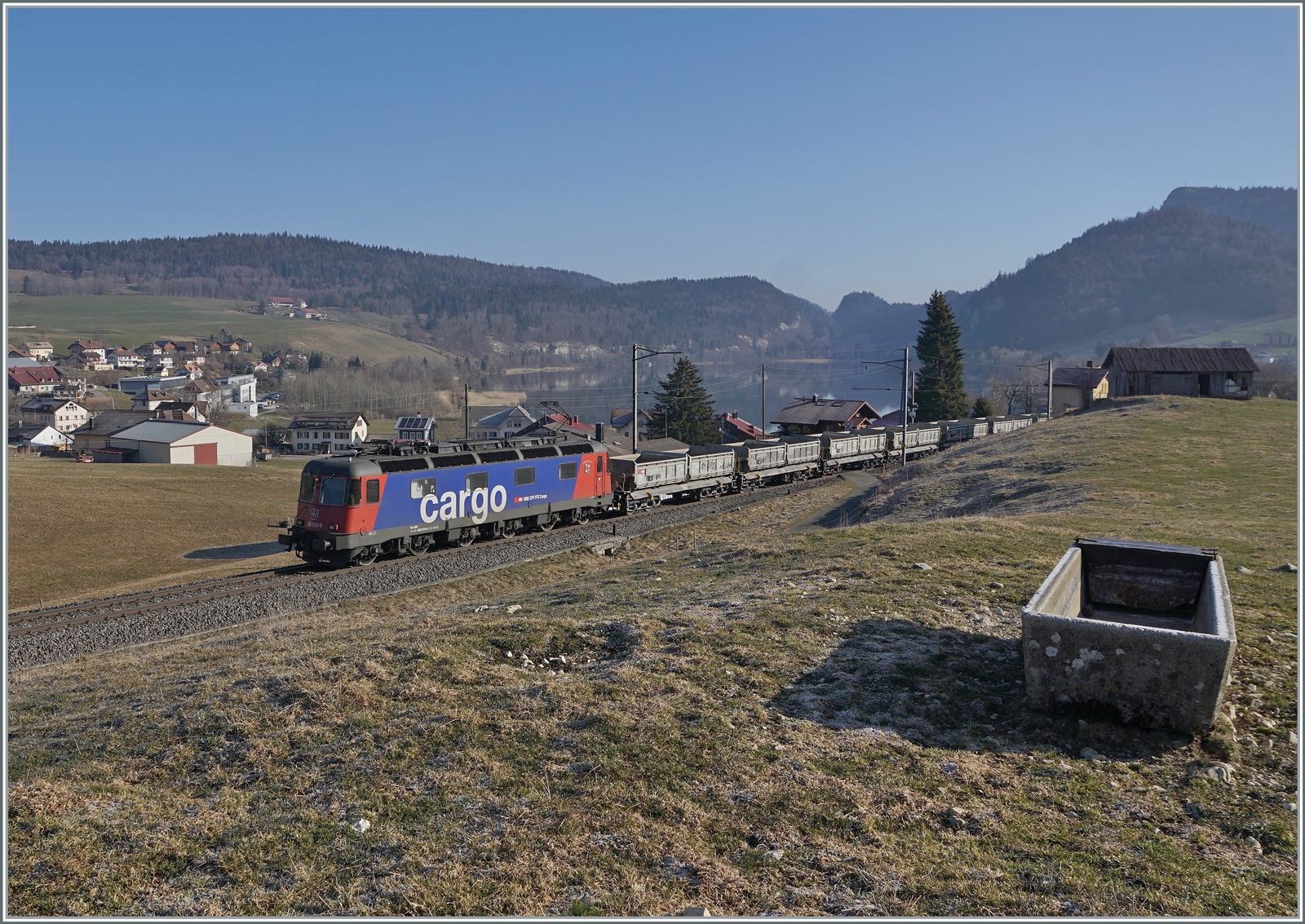 Für wenige Wochen verkehrte ein Güterzug mit einer Re 6/6 in Vallée de Joux - Die SBB Re 6/6 11610 (Re 620 010-9)  Spreitenbach  bringt etliche leere Fans-u Wagen als Güterzug 69701 von Lausanne-Triage nach Le Brassus und konnte hier bei Les Charbonnières mit dem Hintergrund des Lac de Brenet fotografiert werden.

24. März 2022